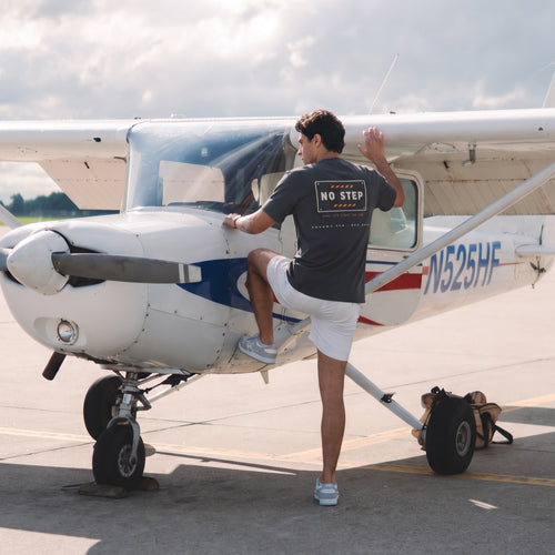 On-model — NO STEP Tee back print, worn while preflighting a Cessna wing, SquawkVFR