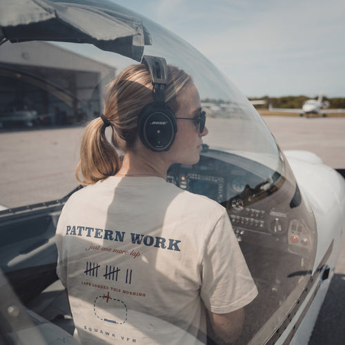 On-model — Pattern Work Tee back print with traffic pattern diagram, worn in the cockpit with a headset, SquawkVFR