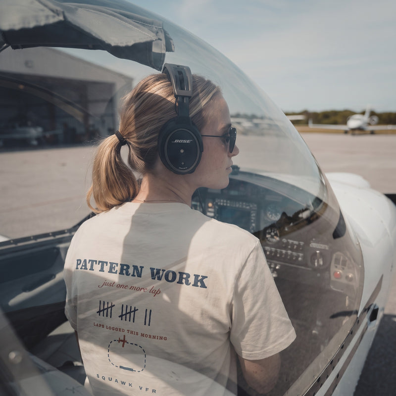 On-model — Pattern Work Tee back print with traffic pattern diagram, worn in the cockpit with a headset, SquawkVFR